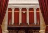 Alito Stays—Conservatives Panic Over Clock Empty courtroom with marble columns and red curtains