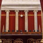 Alito Stays—Conservatives Panic Over Clock Empty courtroom with marble columns and red curtains