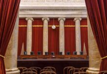 Empty courtroom with marble columns and red curtains