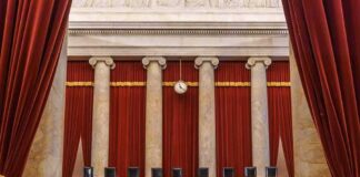 Empty courtroom with marble columns and red curtains