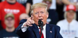 Man in suit pointing, speaking at a rally.