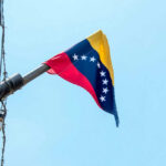 Brain Drain Guts Venezuela’s Comeback Venezuelan flag flying on a pole.