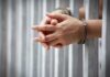 Undercover Sting Nails Party Insider hands in handcuffs behind jail bars