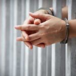 Undercover Sting Nails Party Insider hands in handcuffs behind jail bars