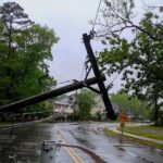 Midwest Darkness Spreads — Numbers Surge Fallen utility poles blocking a wet suburban street