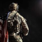 Six Killed — One Sergeant Rushes Toward Fire Soldier in tactical gear with American flag over shoulder