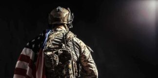 Soldier in tactical gear with American flag over shoulder