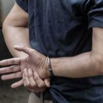 Flag Charge Freezes Yankee Stadium person in handcuffs with hands behind back