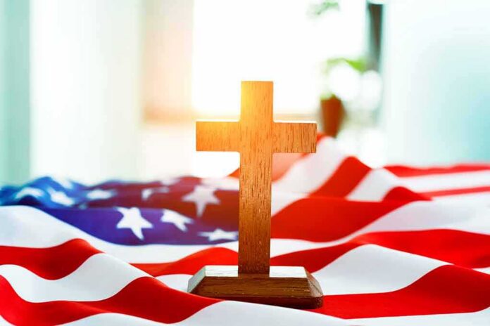 shutterstock_1128600905-1 Wooden cross on an American flag
