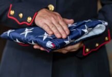 Uniformed person holding a folded American flag