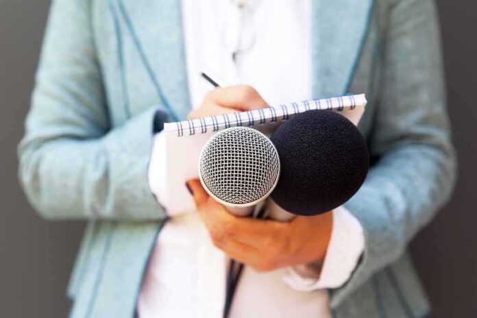 shutterstock_1189499641 Journalist holding microphones and notepad