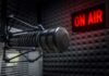 Close-up of a studio microphone with an illuminated on-air sign