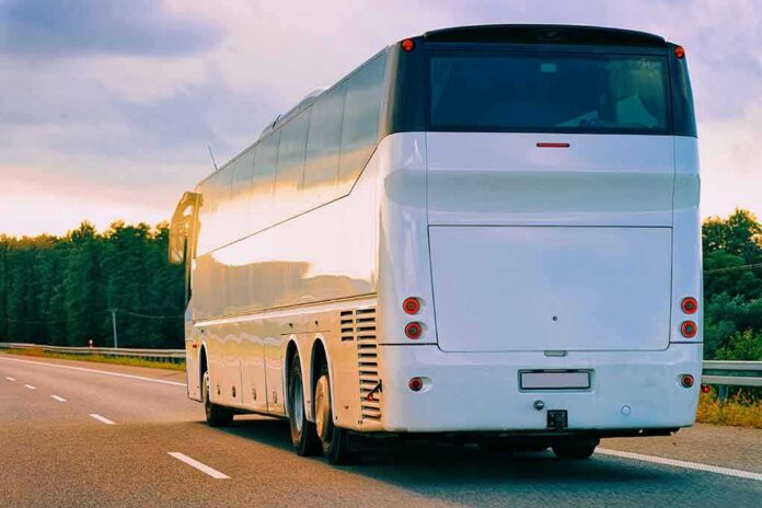 White coach bus driving on a highway at sunset