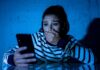 woman covering mouth while looking at smartphone
