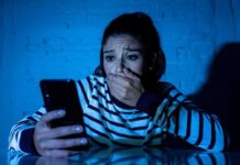woman covering mouth while looking at smartphone