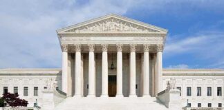 Front view of the Supreme Court building with large columns and steps under a blue sky