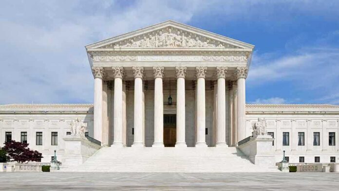 Front view of the Supreme Court building with large columns and steps under a blue sky