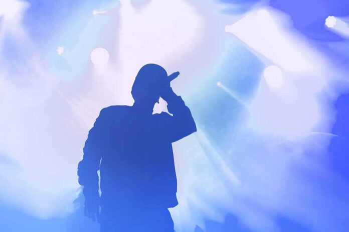 shutterstock_1482376136 Silhouette of a singer holding a microphone on stage
