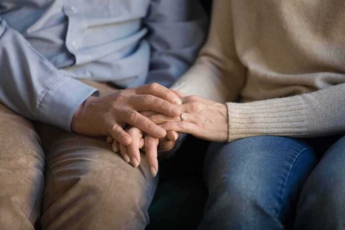 shutterstock_1498195019 Couple holding hands on a couch