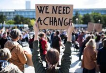 NYC’s Youth Drain – Sticker Shock Sends New Yorkers South Person holding protest sign above head at a crowded rally