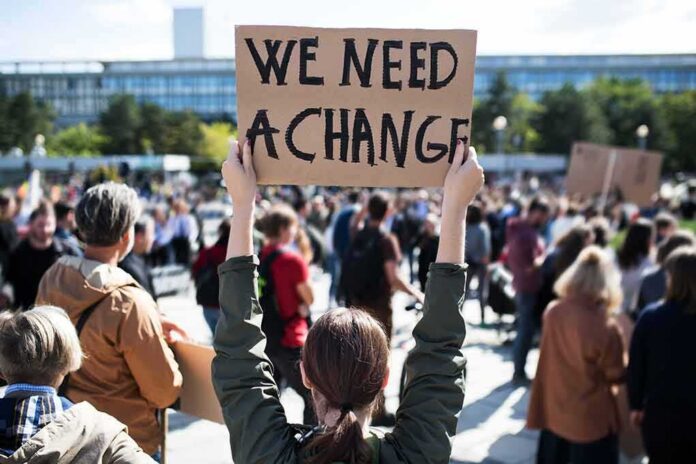 Person holding protest sign above head at a crowded rally