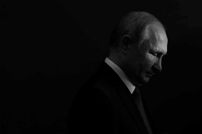 Vladimir Putin in profile, side-lit against a dark background