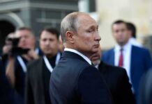 Russia’s Rarest Jet Strikes From Sanctuary man in suit looking back in a crowd