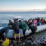 People arriving in a crowded inflatable boat at a rocky shore