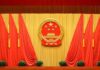 Chinese national emblem on red-draped stage backdrop