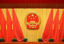 China Imagery Tied To Deadly Iran Strike Chinese national emblem on red-draped stage backdrop