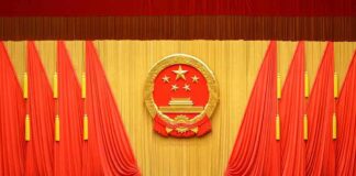 Chinese national emblem on red-draped stage backdrop