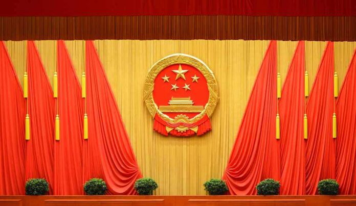 shutterstock_1697991220 Chinese national emblem on red-draped stage backdrop