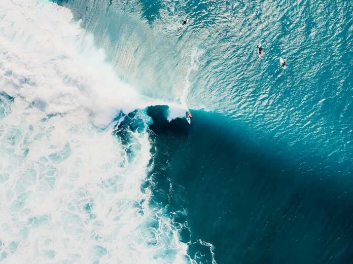 shutterstock_1722733663 Surfer riding a large turquoise wave from above