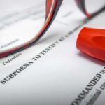 Subpoena document with red highlighter and eyeglasses