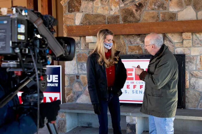 shutterstock_1887168877 Kelly Loeffler speaks with a man during an on-camera interview at a stone-walled venue