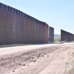 Border wall along a dusty desert road
