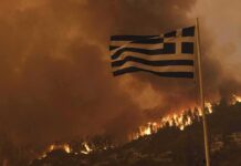 Greek flag over hillside wildfire