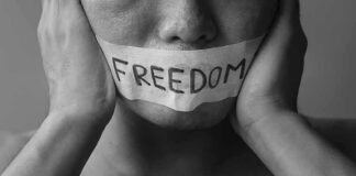 person with taped mouth holding their face