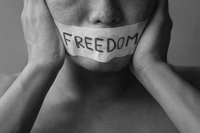 person with taped mouth holding their face