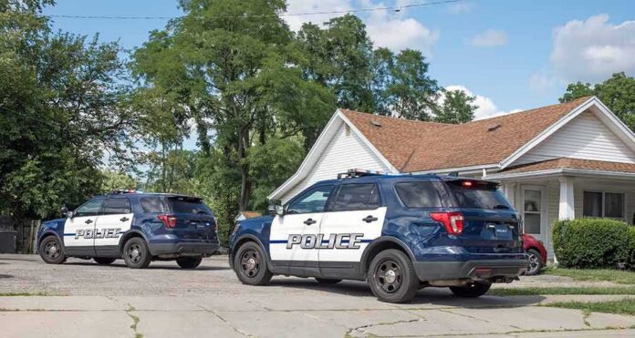 shutterstock_2195086633-1 Two police SUVs parked near a suburban house
