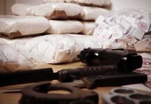 Piles of bagged powder with a handgun on a table