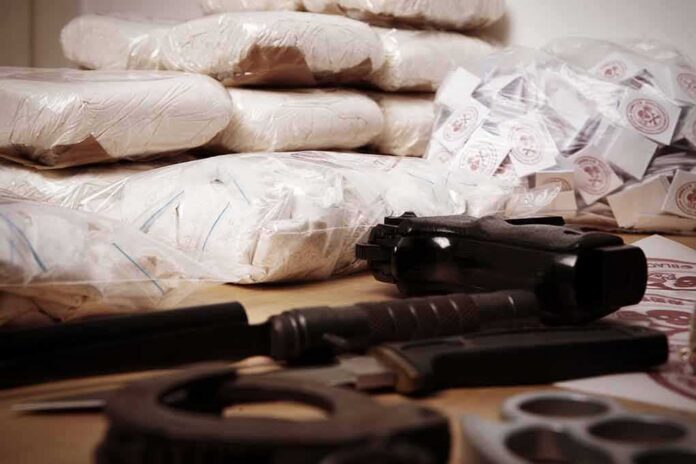 Piles of bagged powder with a handgun on a table