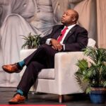 Tim Scott’s ‘Radical And Weird’ Broadside Man in suit seated in white armchair on stage