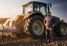 Farmer standing beside a tractor in a plowed field