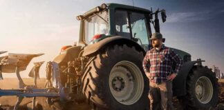 Farmer standing beside a tractor in a plowed field