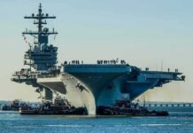 Eisenhower Scare: Deck Disaster Sparks Navy Probe Aircraft carrier guided by tugboats in a harbor