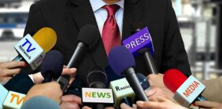 Press microphones surround a suited spokesperson