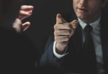 Man in suit pointing a finger during a tense conversation