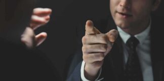 Man in suit pointing a finger during a tense conversation