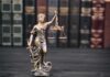 Life-Insurance Kill? Clemency Shot Down Lady Justice statue with scales in front of law books